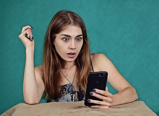 Woman shocked looking at mobile phone - Overoptimized LinkedIn profile